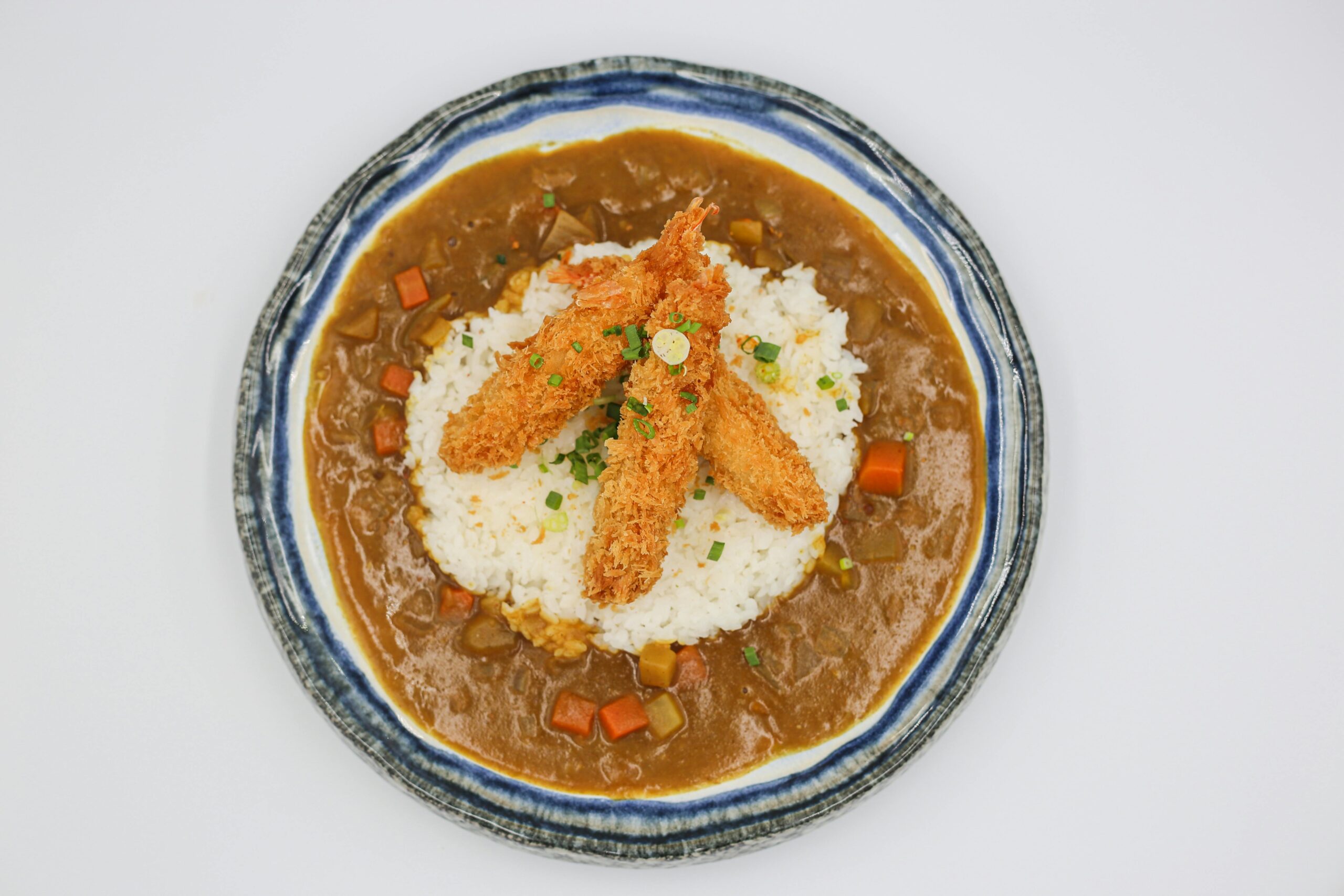 Delicious ebi tempura served on rice with curry sauce for a flavorful Japanese meal.